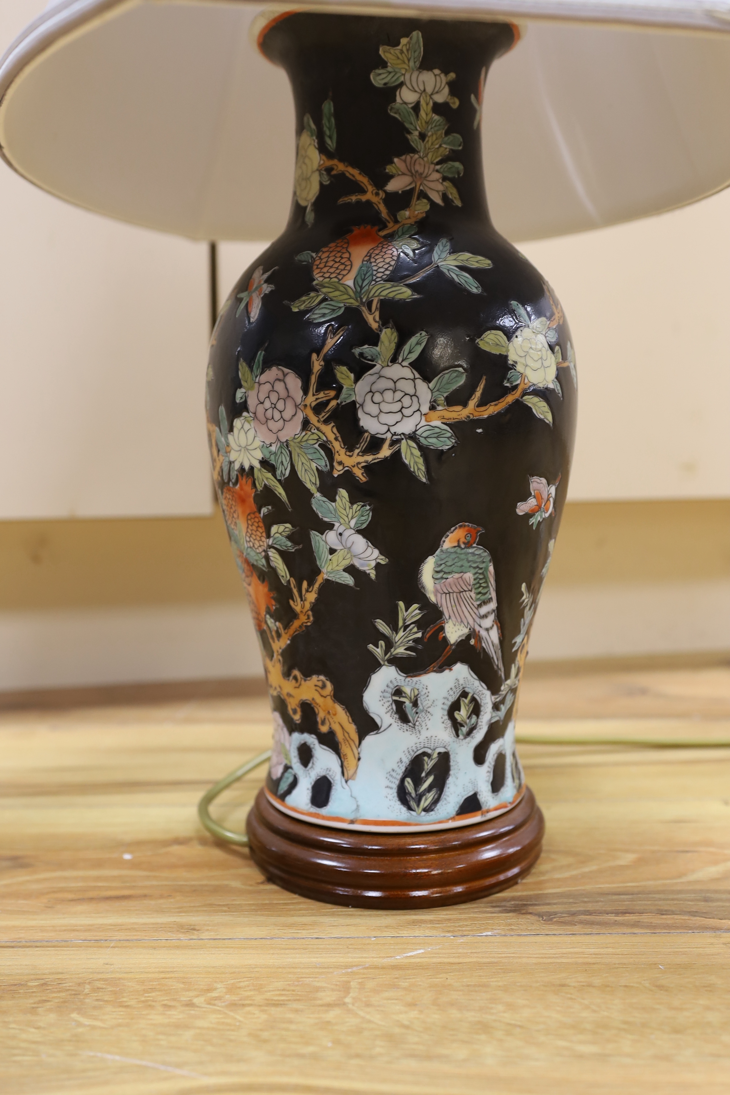 A Chinese famille noire table lamp and a pink ground Chinese vase, both on wooden stands, tallest vase 39cm